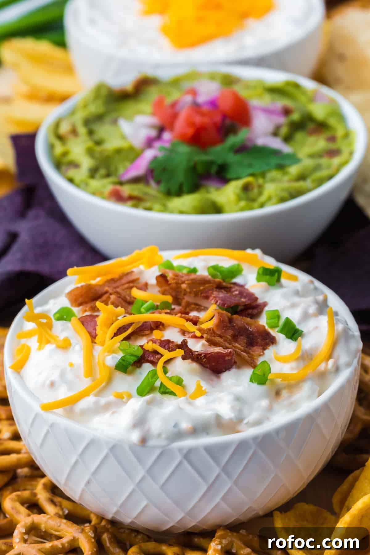 Creamy Loaded Baked Potato Dip Recipe for Parties 7 A small white bowl filled with baked potato dip, topped with cheddar cheese, bacon, and green onion.