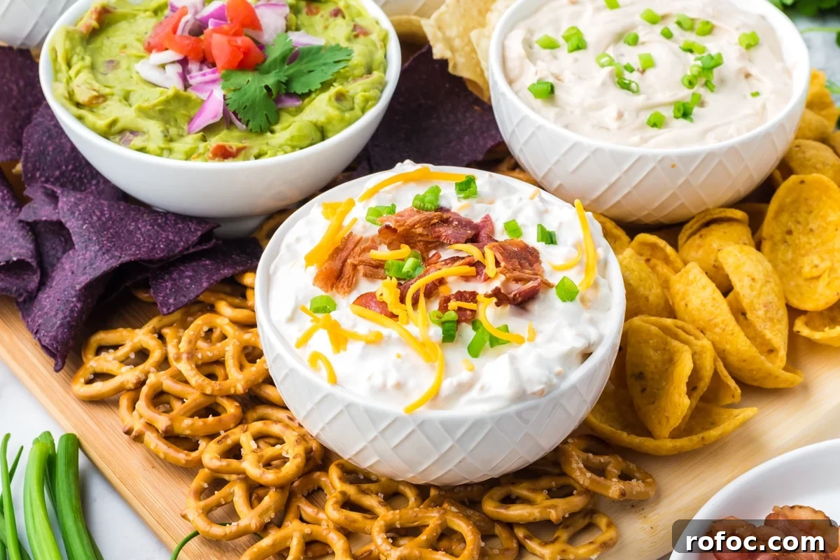 Creamy Loaded Baked Potato Dip Recipe for Parties 8 Three bowls of various dips, surrounded with blue corn tortilla chips, corn chips, and pretzels.