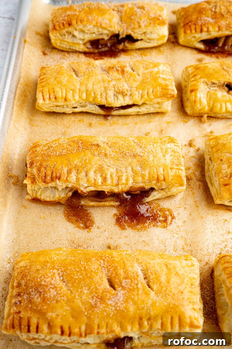 Homemade Apple Hand Pies: Flaky Mini Pastry Recipe 6 Baked apple hand pies on a baking sheet after coming out of the oven.