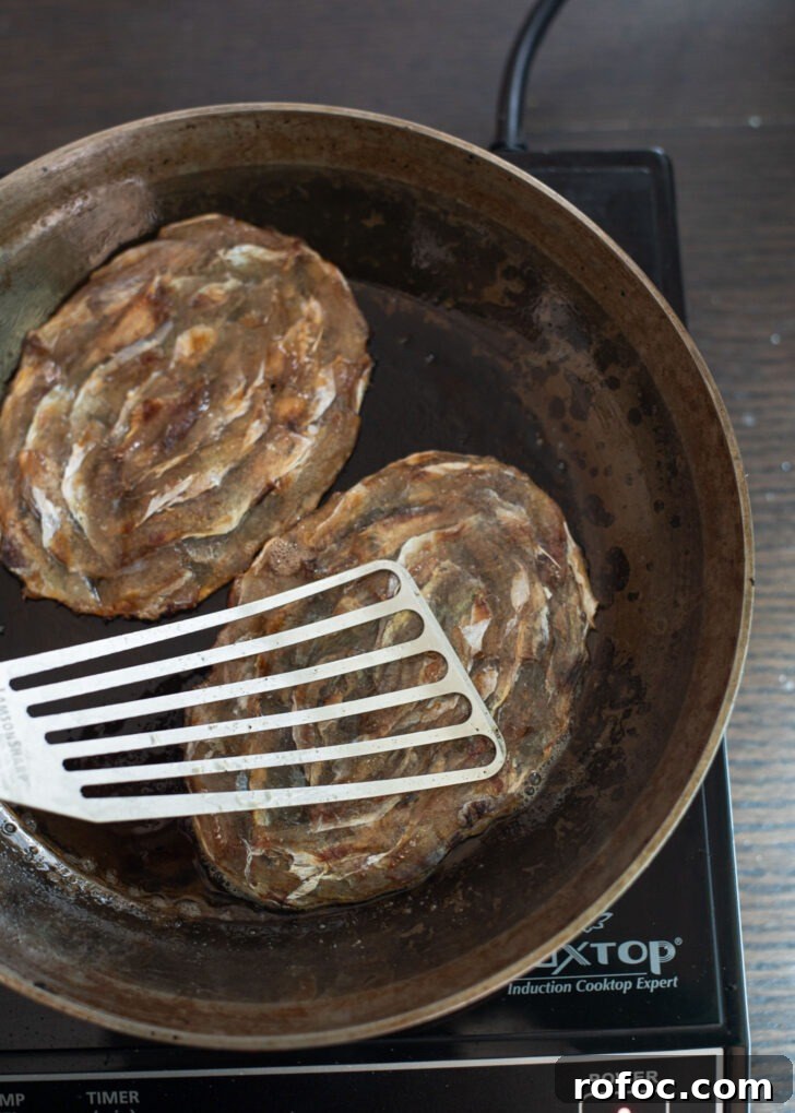 Korean-Style Jwipo Fish Jerky: Spicy Dried Fish Snack Guide 8 A spatula is pressing dried filefish roasting in skillet.