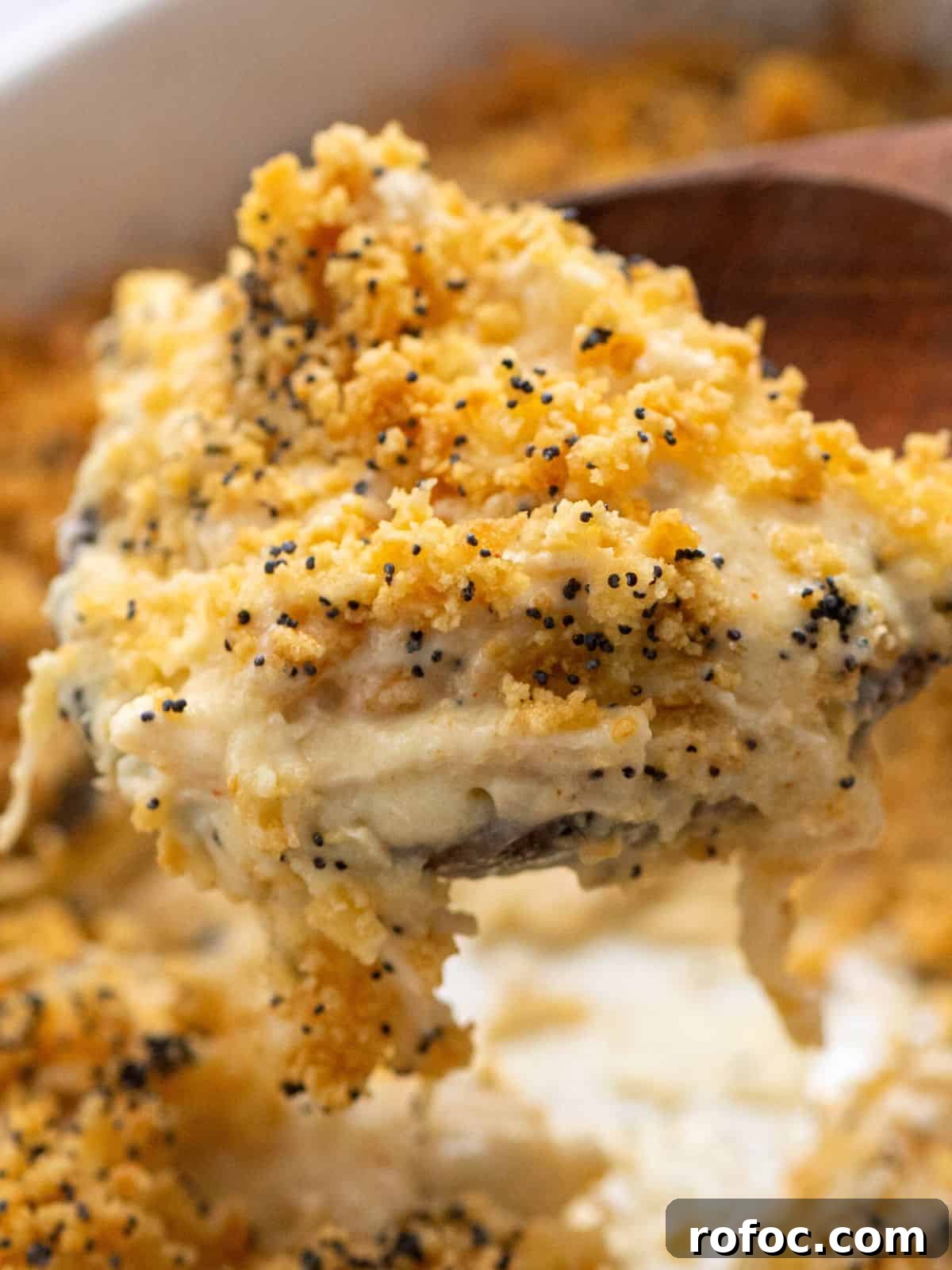 Poppy Seed Chicken Recipe Spoonful of chicken poppy seed casserole coming out of casserole dish.