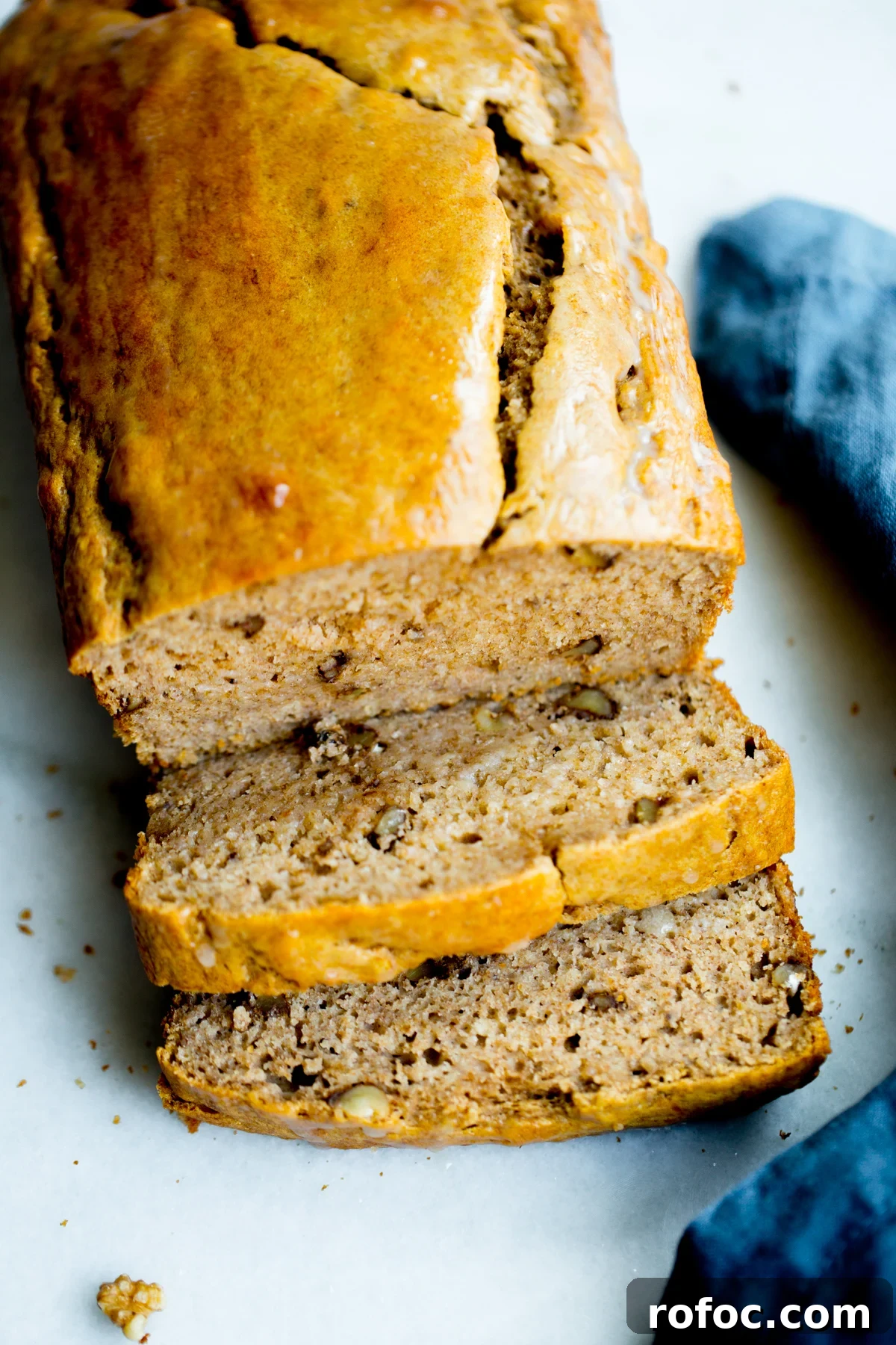 close up photo of a loaf of healthy banana bread with walnuts on marble background with a blue napkin