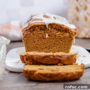 Moist Pumpkin Bread Made with Cake Mix in 1 Bowl 8 The pumpkin bread is on a cutting board with a drip of the icing coming off the front.