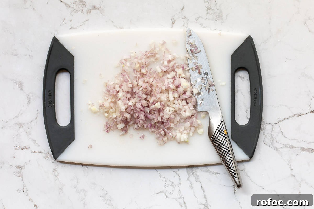 Creamy Baked Crab Dip with Garlic and Parmesan 5 chopped shallots on cutting board.