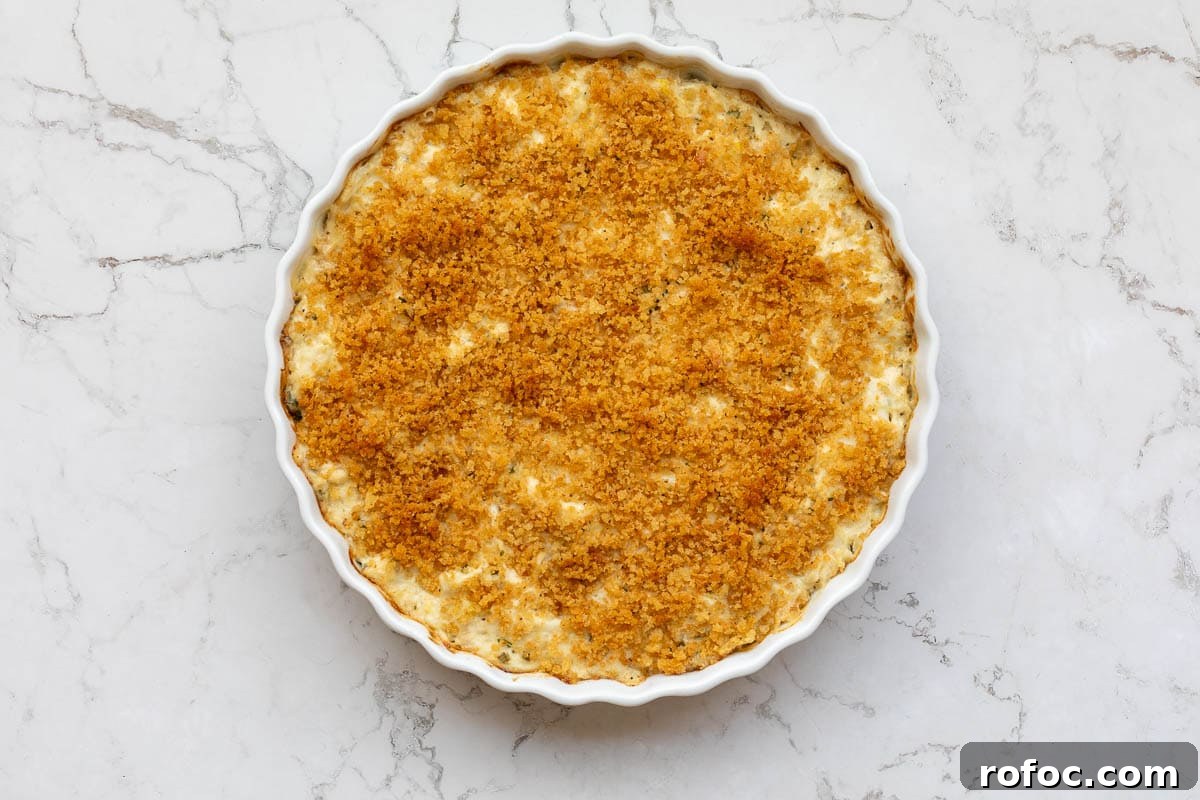 Creamy Baked Crab Dip with Garlic and Parmesan 9 hot baked crab dip topped with breadcrumbs in baking dish.