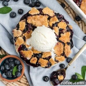 Blueberry Cake Mix Cobbler: Quick, Moist Dessert Recipe 13 Blueberry cobbler with cake mix in a round dish with ice cream on top and fresh blueberries on the side.