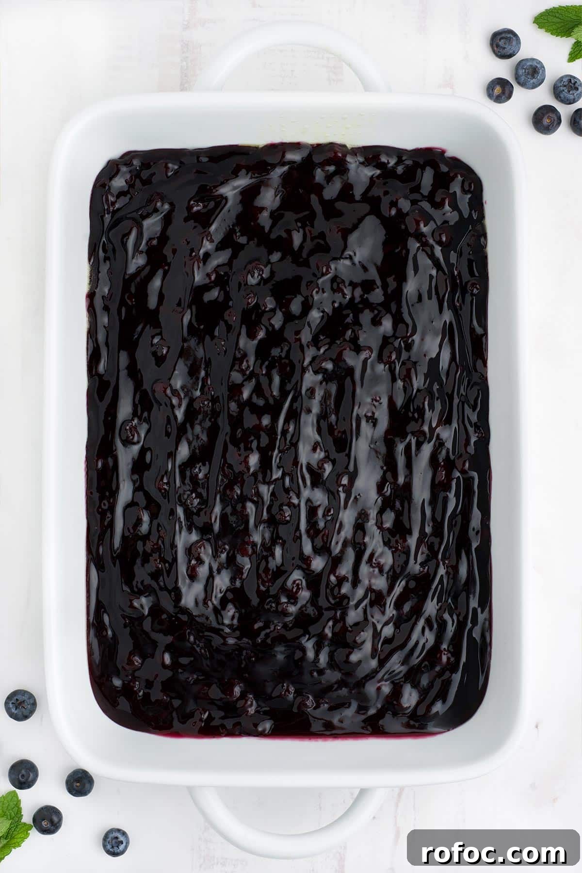 Blueberry Cake Mix Cobbler: Quick, Moist Dessert Recipe 4 Blueberry pie filling spread out in a white casserole dish.