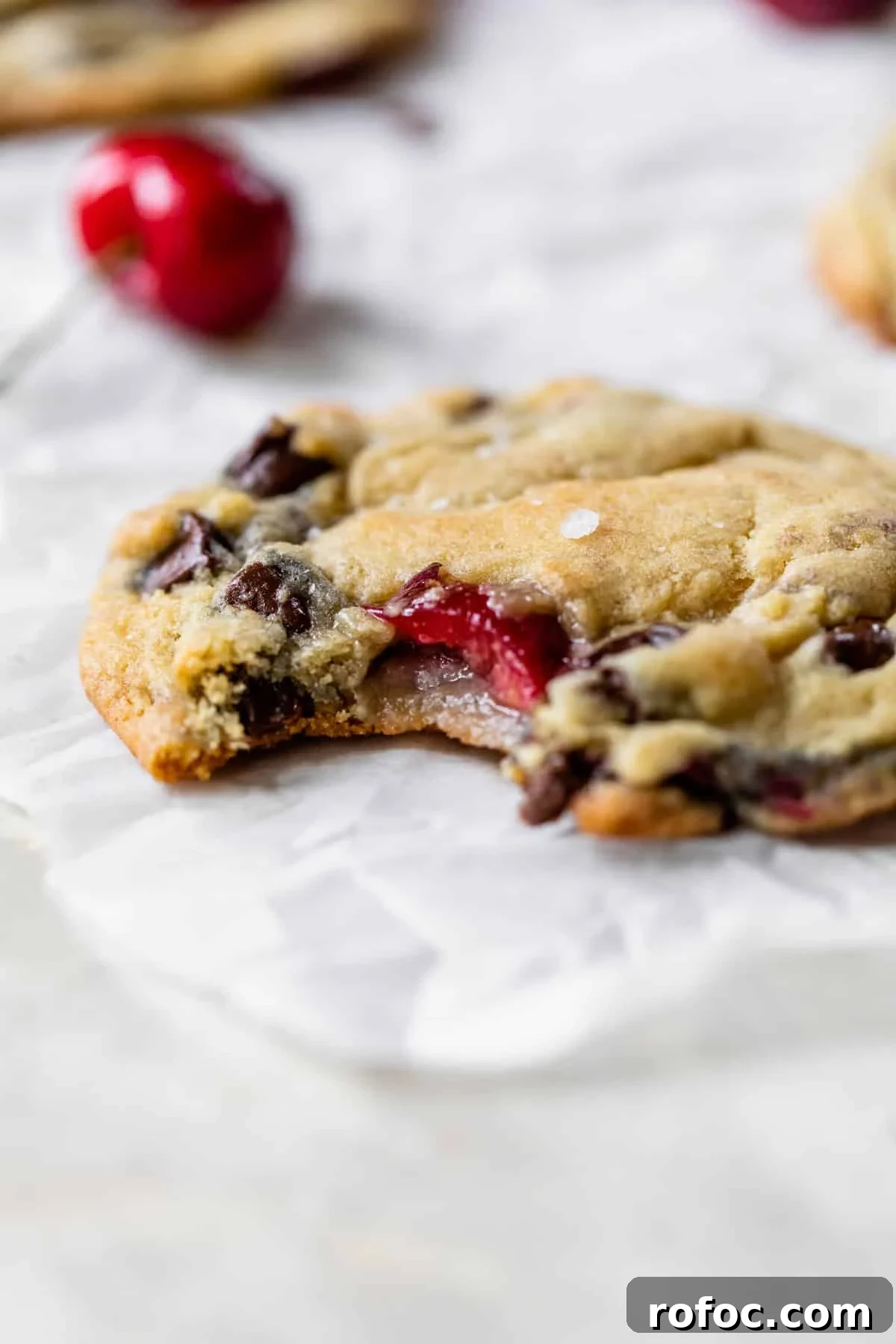 a chocolate chip cookie with cherries in it with a bite taken out of it