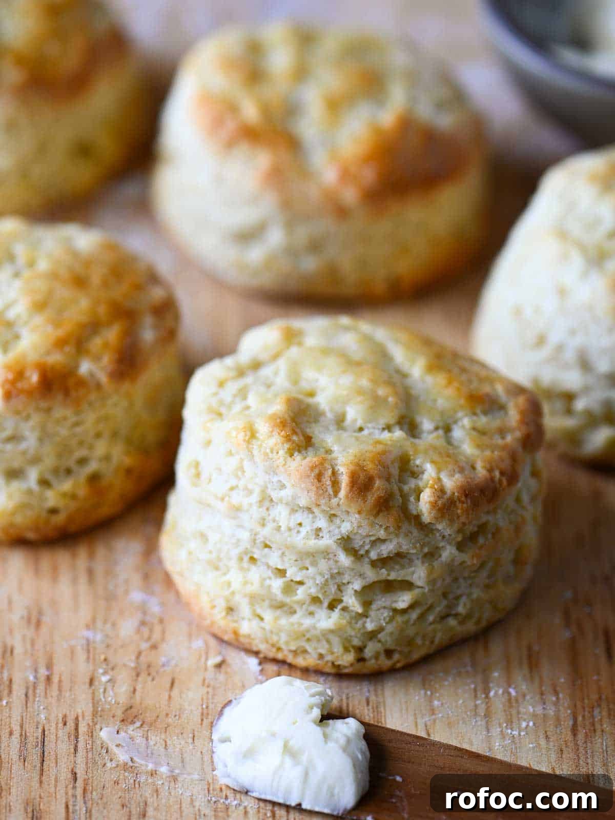 Golden biscuits on a cutting board next to a knife with butter on it.