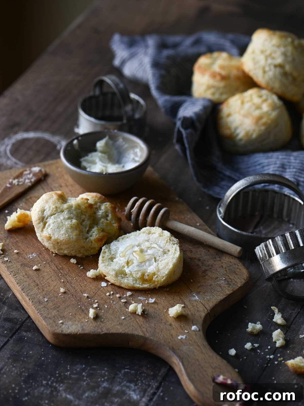 Angled view of a table breakfast scene with biscuits, butter and crumbs scattered around it.
