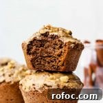 two chai muffins stacked on each other with a bite taken out of the top muffin and cinnamon sticks in a jar in the back