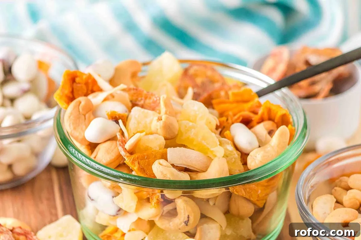 50 Quick Dinner Ideas to Make When You Don't Feel Like Cooking 6 A glass jar filled with tropical trail mix dried fruits and nuts on a wooden table with a colorful cloth in the background.