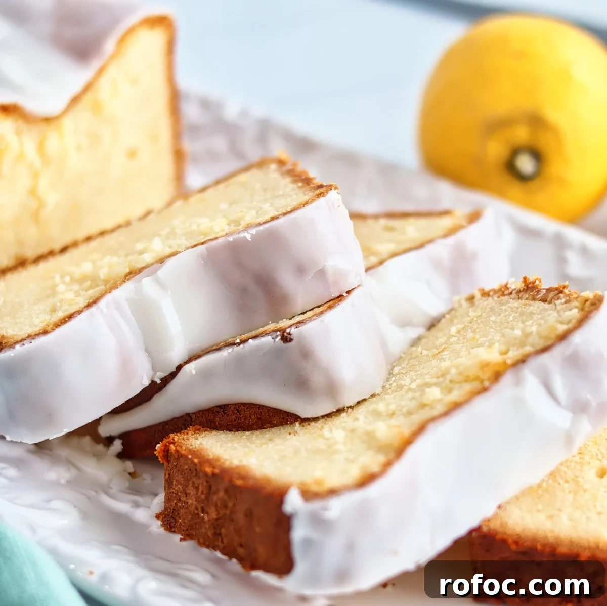 Gluten-Free Lemon Loaf: Starbucks Copycat Recipe for Moist Zest 2 slices of gluten free lemon loaf cake on white rectangular platter with whole lemons in the background.