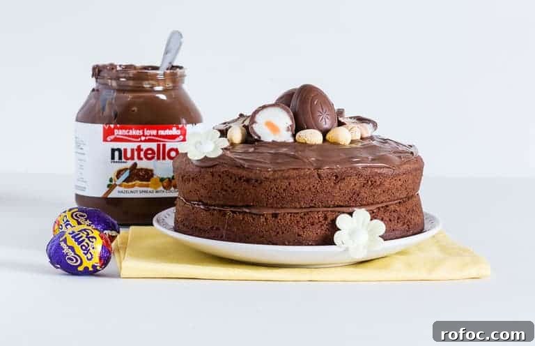 Nutella Crème Egg Cake with Silky Nutella Frosting 3 Easy Nutella Cake topped with nutella frosting and some cadbury creme eggs, with a jar of nutella at the back