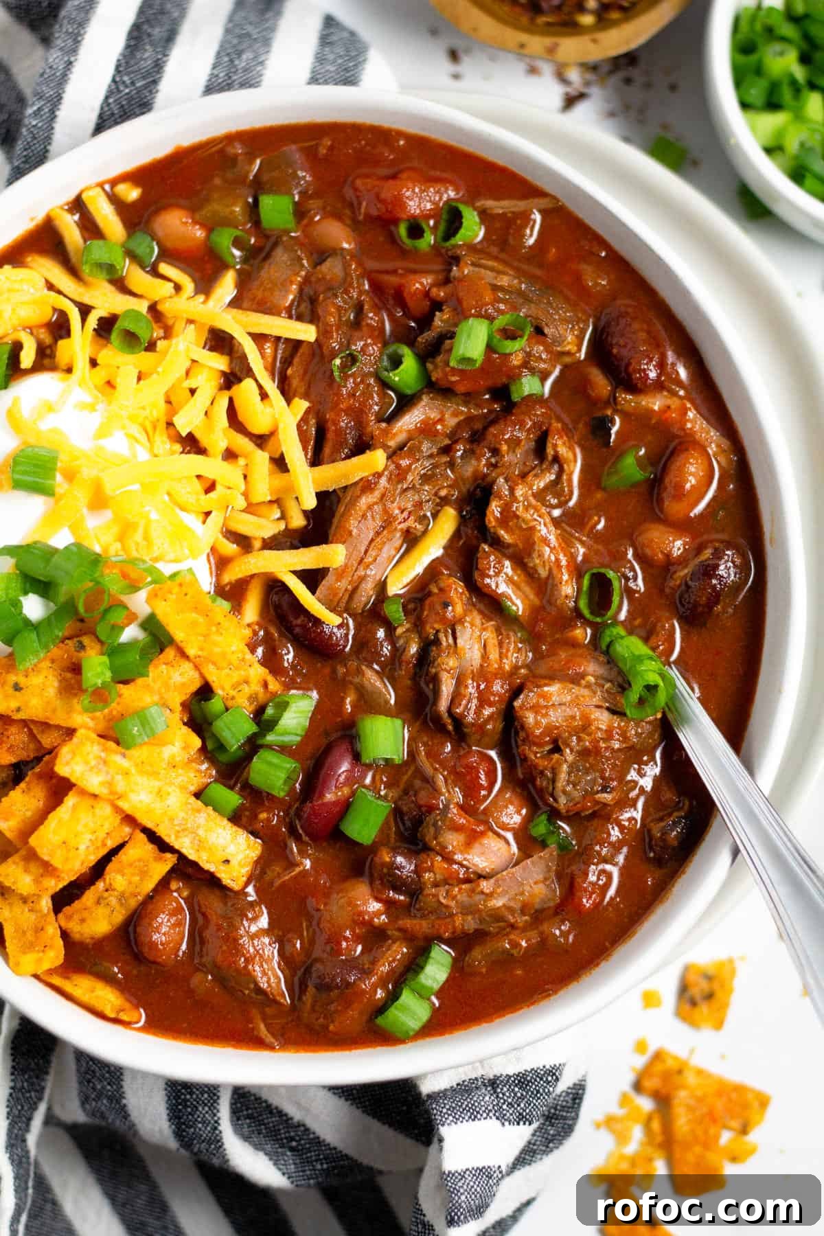 Overhead shot of a bowl of short rib beef chili topped with sour cream and cheese