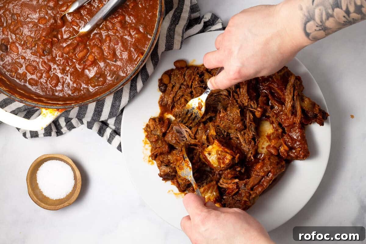 Two forks shredding beef short ribs