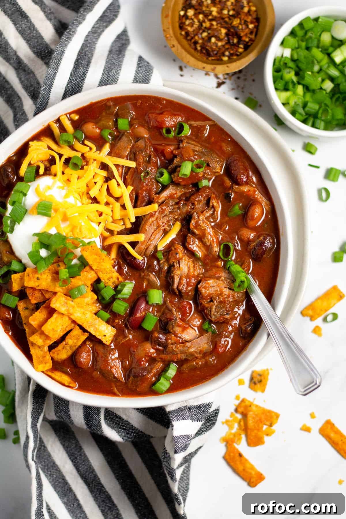 Overhead shot of a bowl of short rib beef chili topped with sour cream and cheese