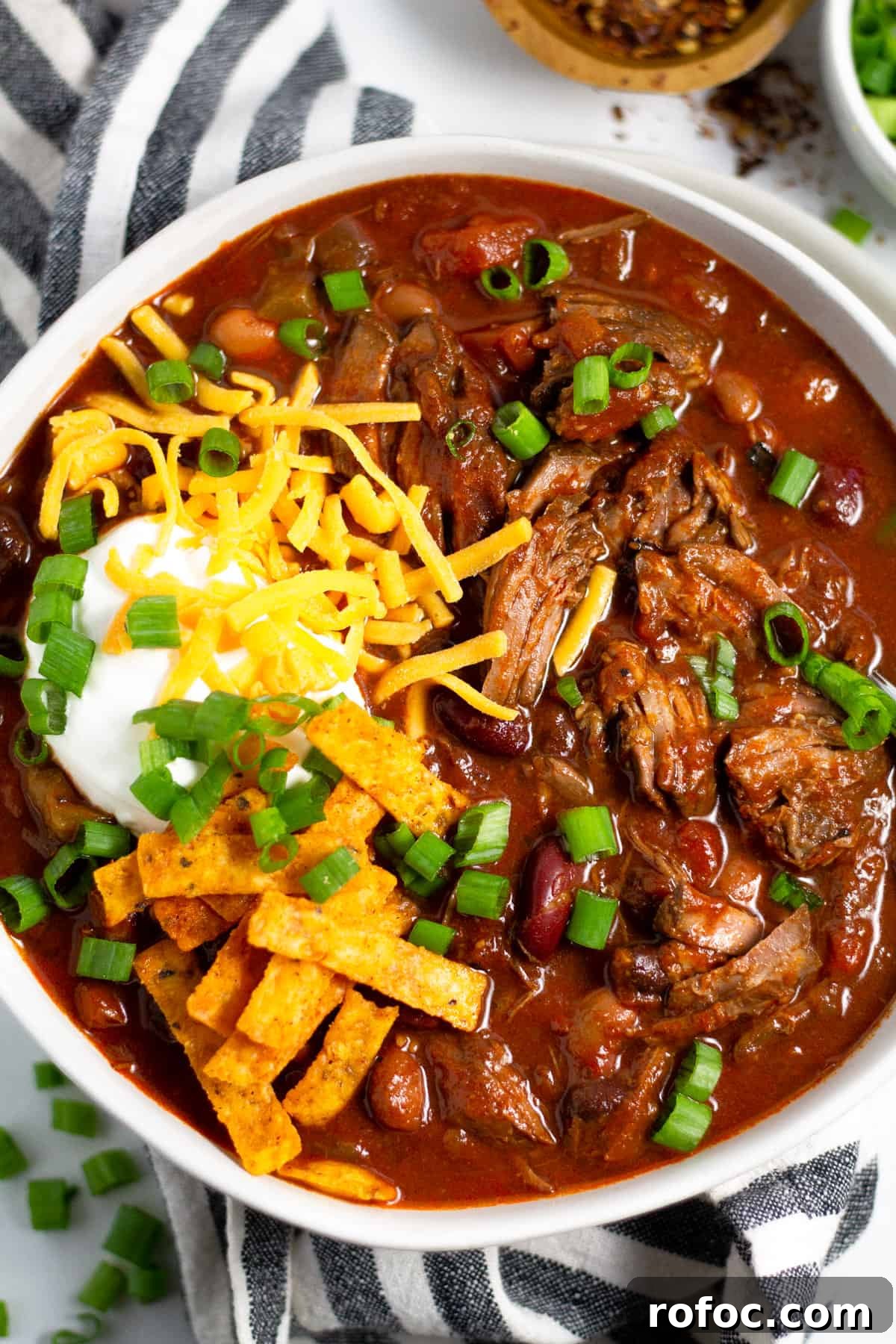 Overhead shot of a bowl of short rib beef chili topped with sour cream and cheese