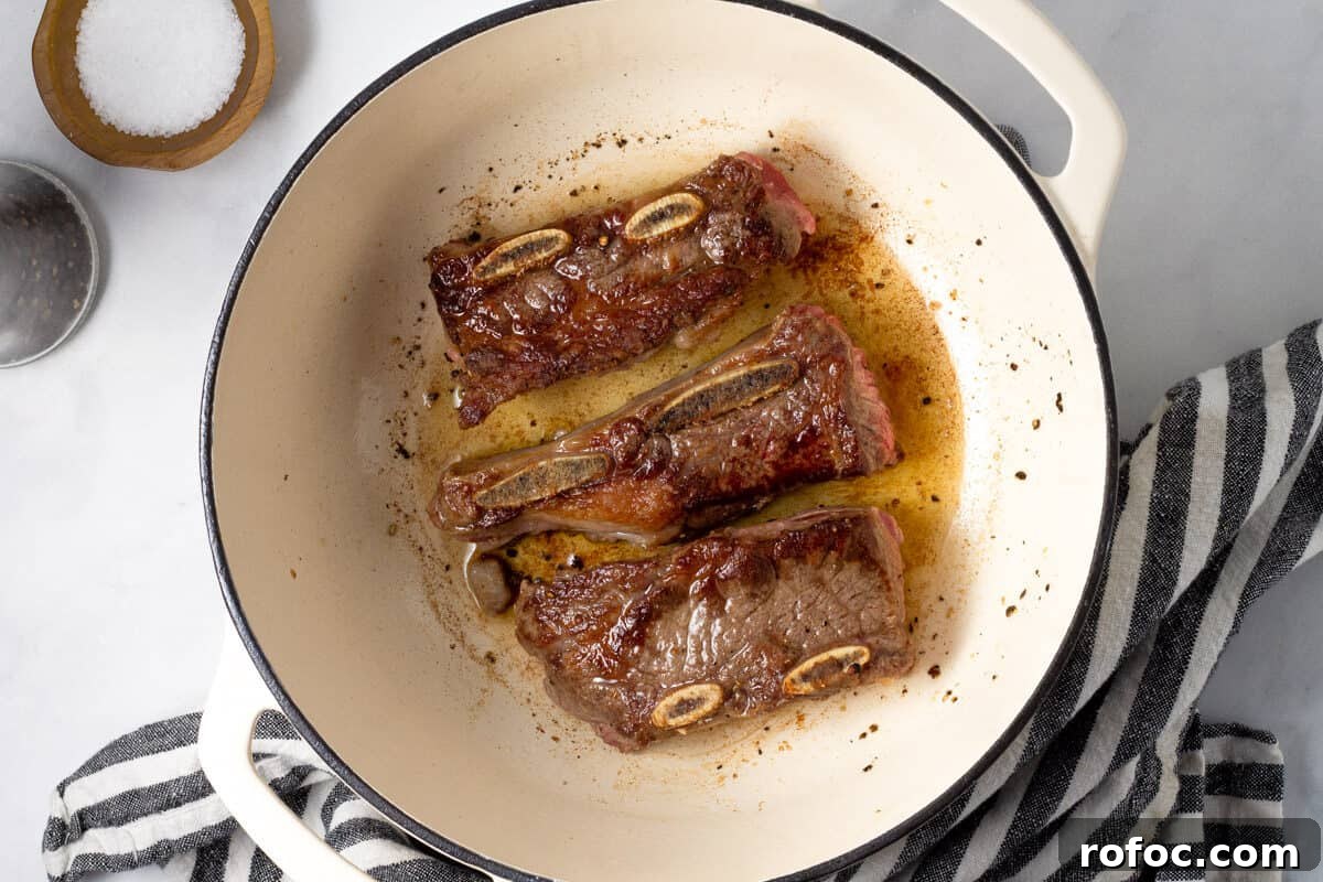 Large white pot filled with seared short ribs