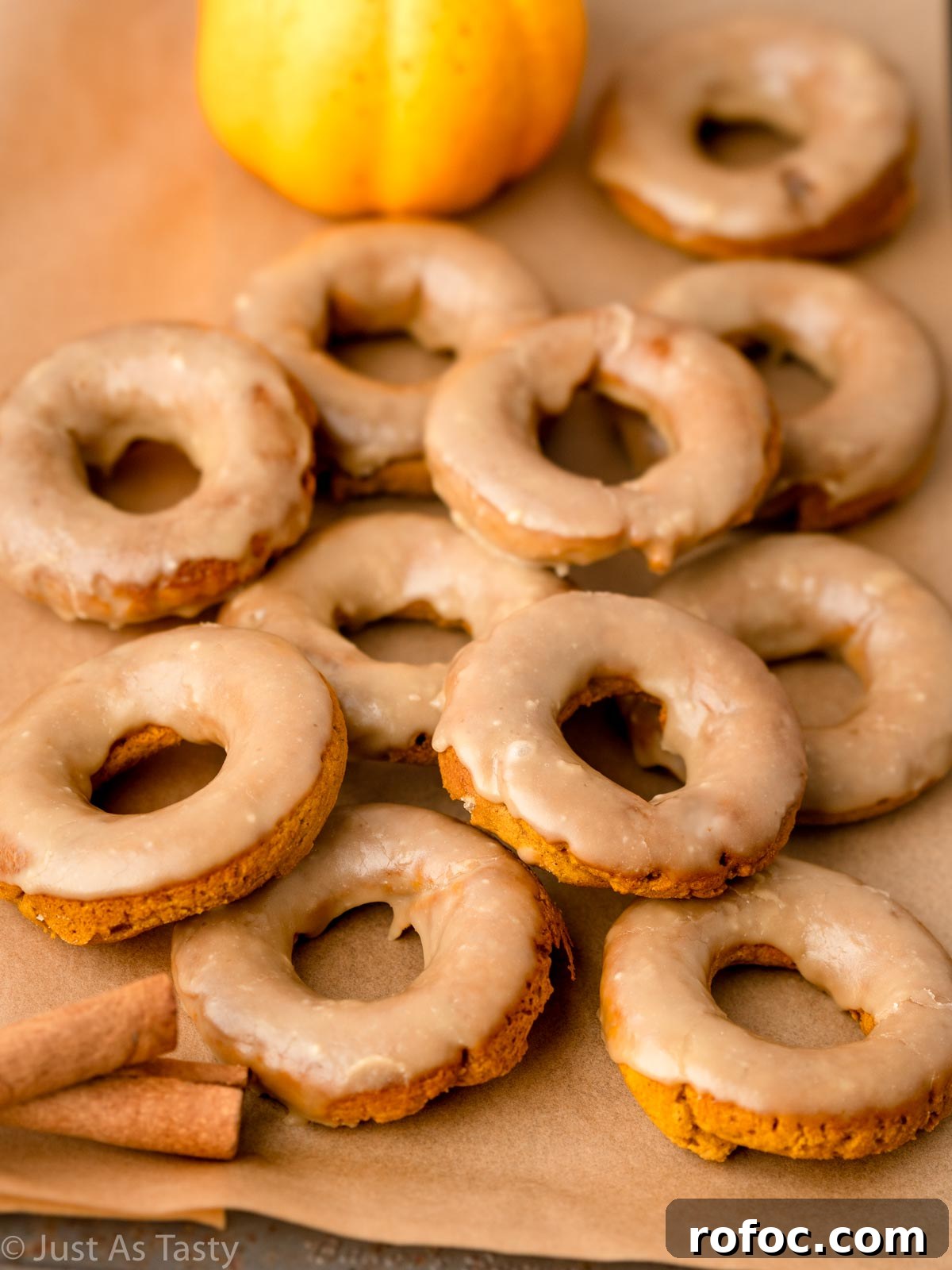 Pumpkin Spice Donuts with Maple Glaze: Fall Recipe Delight 3 Pumpkin spice donuts on a lined baking sheet.