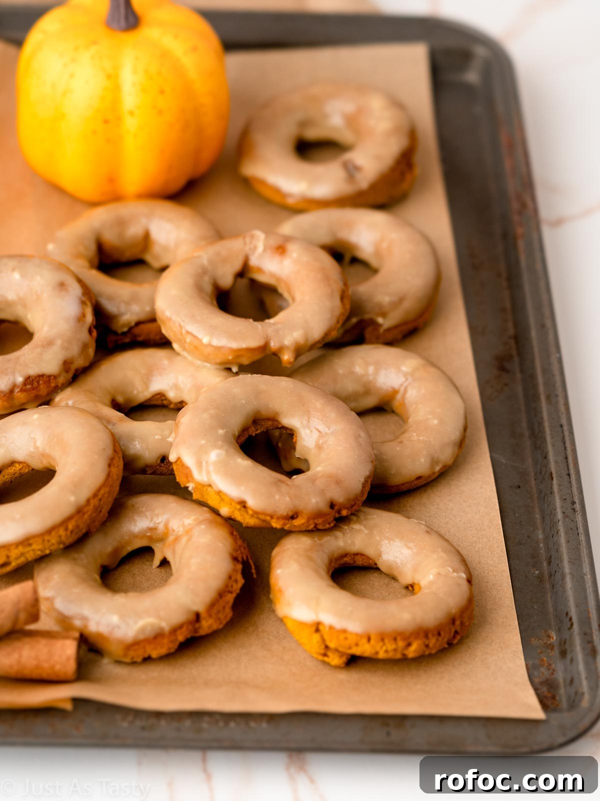 Pumpkin Spice Donuts with Maple Glaze: Fall Recipe Delight 6 Maple glazed pumpkin spice donuts on a baking sheet.