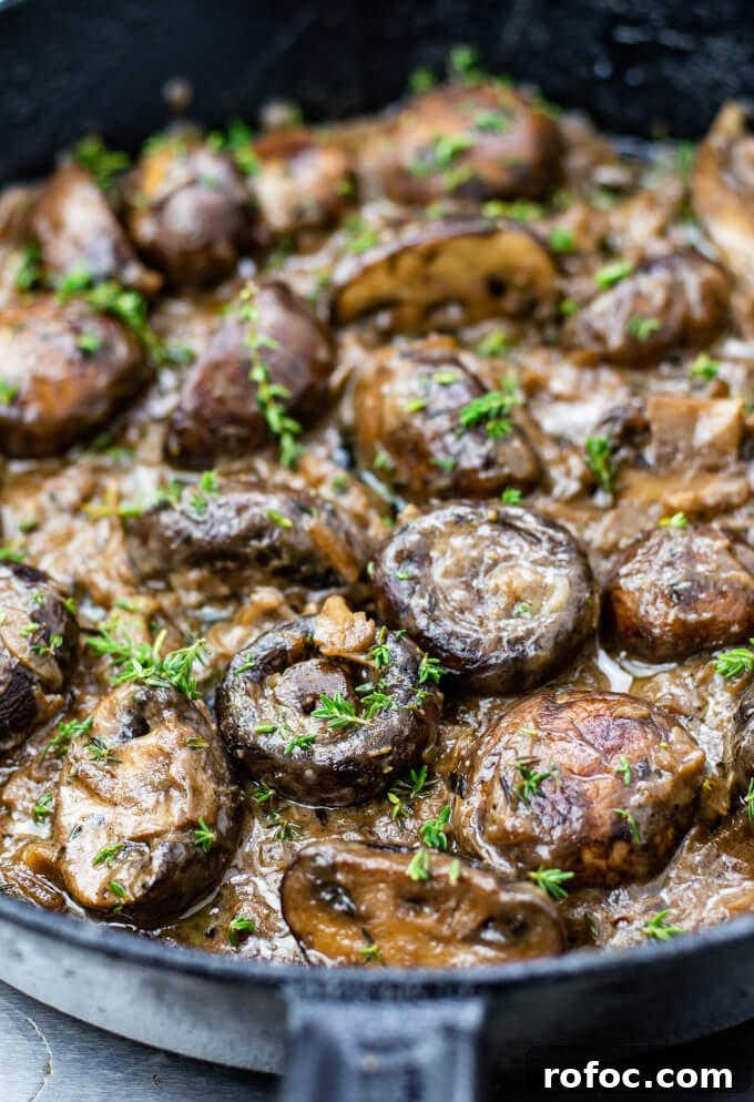 Creamy Mascarpone Garlic Mushrooms with Herbs and Toasted Bread 2 A clos-up photo of sautéed mushrooms in a creamy sauce with chopped thyme sprinkled on top. All of this is in a cast iron skillet.