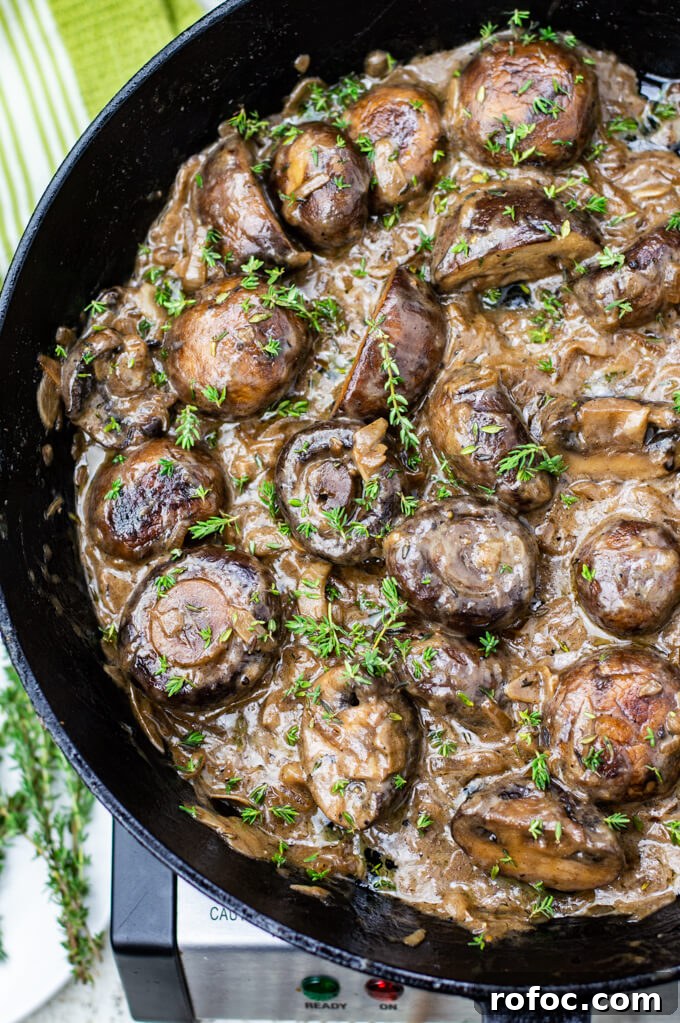 Creamy Mascarpone Garlic Mushrooms with Herbs and Toasted Bread 8 A clos-up photo of sautéed mushrooms in a creamy sauce with chopped thyme sprinkled on top. All of this is in a cast iron skillet.