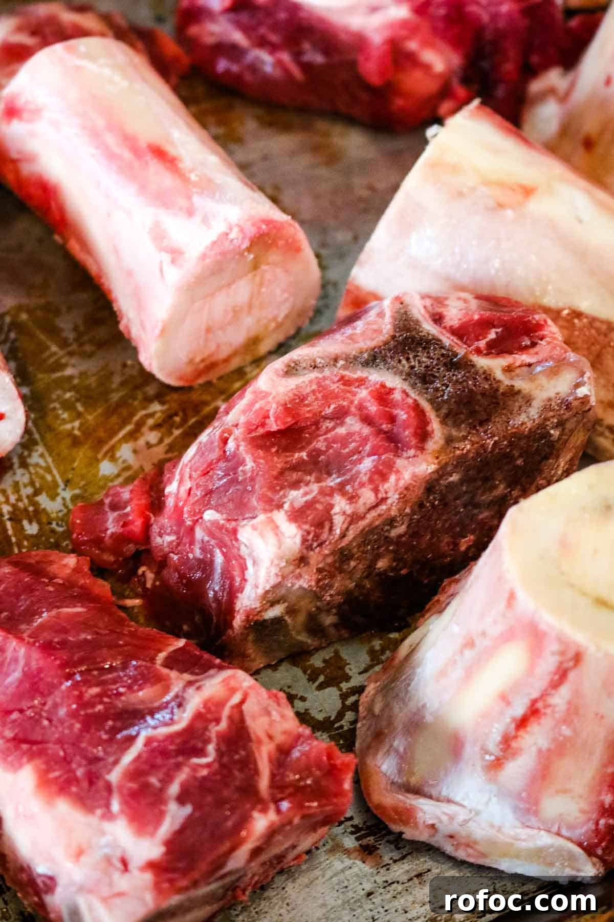 Rich Homemade Beef Bone Broth Recipe for Deep Flavor and Nutrition 4 soup bones on a sheet for roasting.