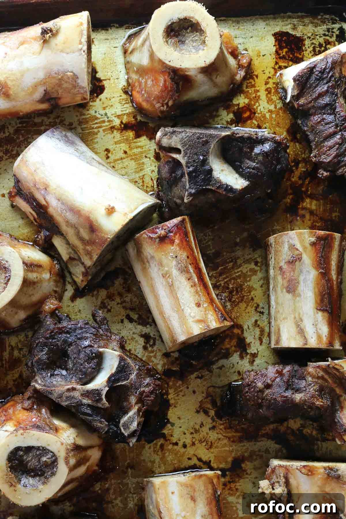 Rich Homemade Beef Bone Broth Recipe for Deep Flavor and Nutrition 7 roasted bones on a baking sheet.