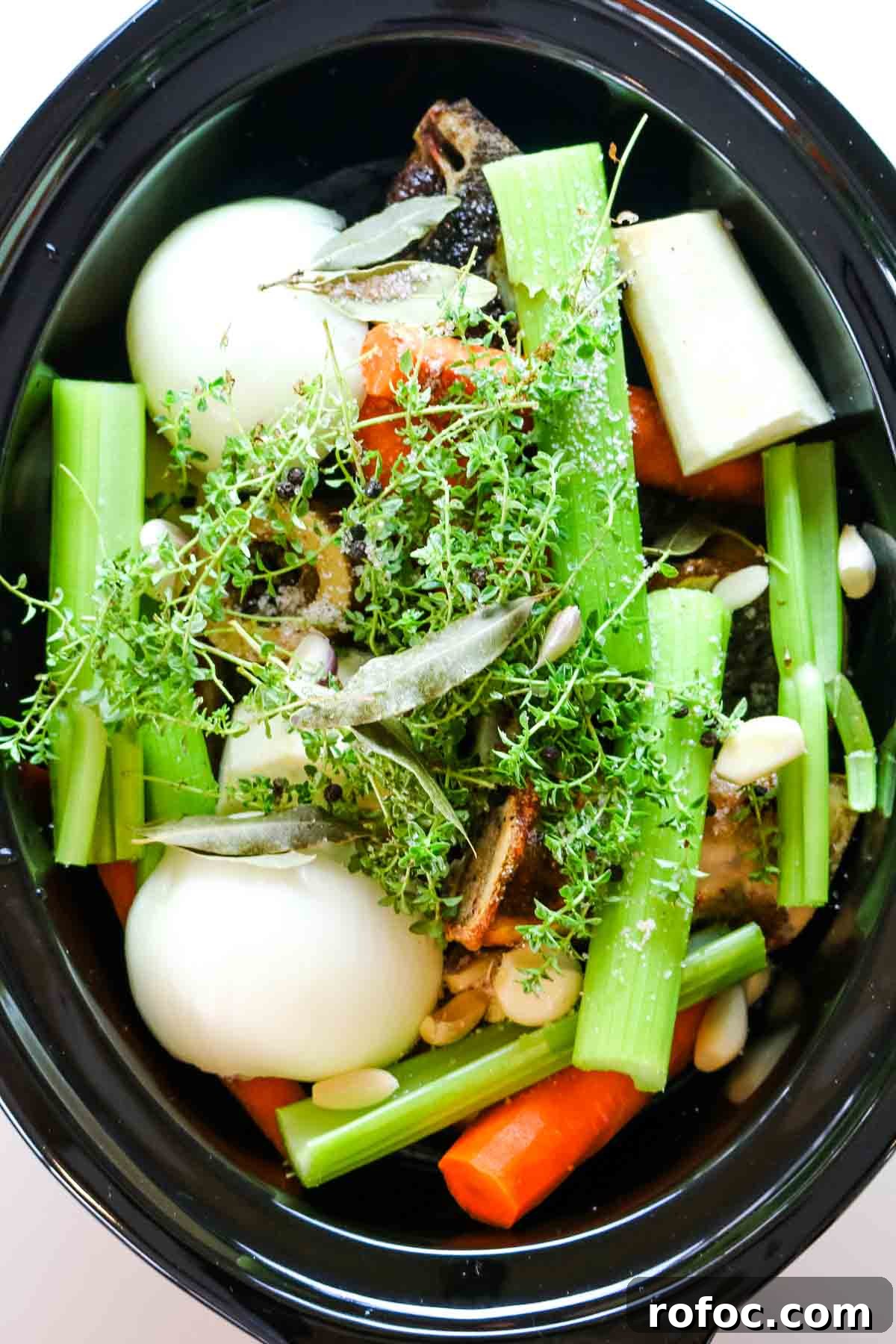 Rich Homemade Beef Bone Broth Recipe for Deep Flavor and Nutrition 8 vegetables added to beef bone broth in slow cooker.