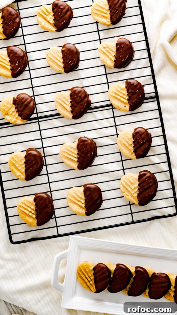 Heart-Shaped Peanut Butter Cookies Recipe for Valentine’s Day 5 Heart Peanut Butter Cookies dipped in chocolate on black cooling rack and on white rectangular serving platter.
