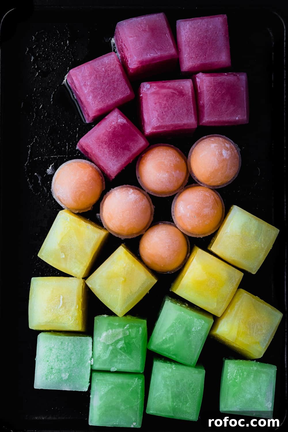 Spiced Watermelon Popsicles: Vibrant, Refreshing Summer Treat 4 Red, orange, yellow and green melon ice; overhead shot on a black background