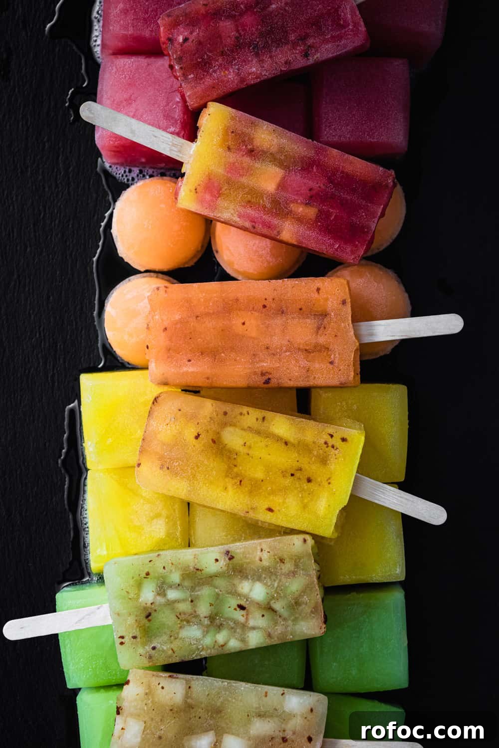 Spiced Watermelon Popsicles: Vibrant, Refreshing Summer Treat 5 Colorful melon popsicles on top of red, orange, yellow and green melon ice.