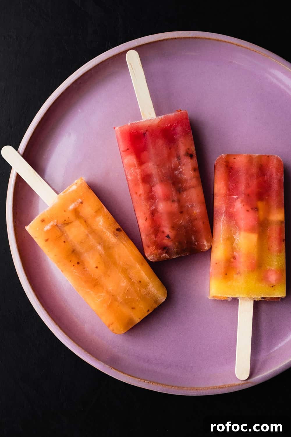 Spiced Watermelon Popsicles: Vibrant, Refreshing Summer Treat 6 3 colorful watermelon popsicles on a pink plate; overhead shot on a black background