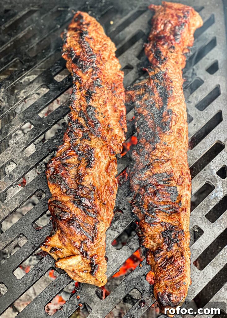 charred skirt steak on a grill over hot coals