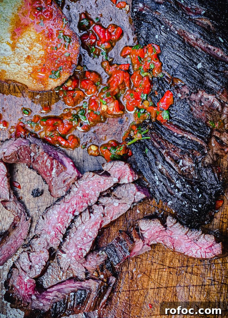 sliced skirt steak on a cutting board with red chimichurri
