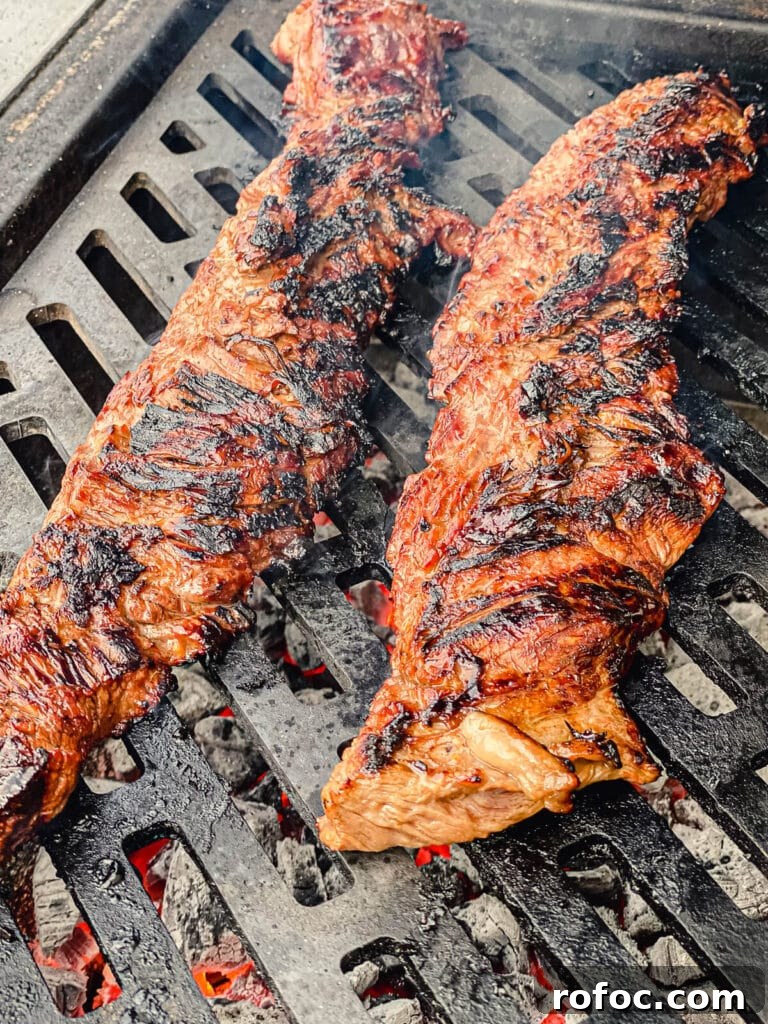 charred skirt steaks on a grill grate