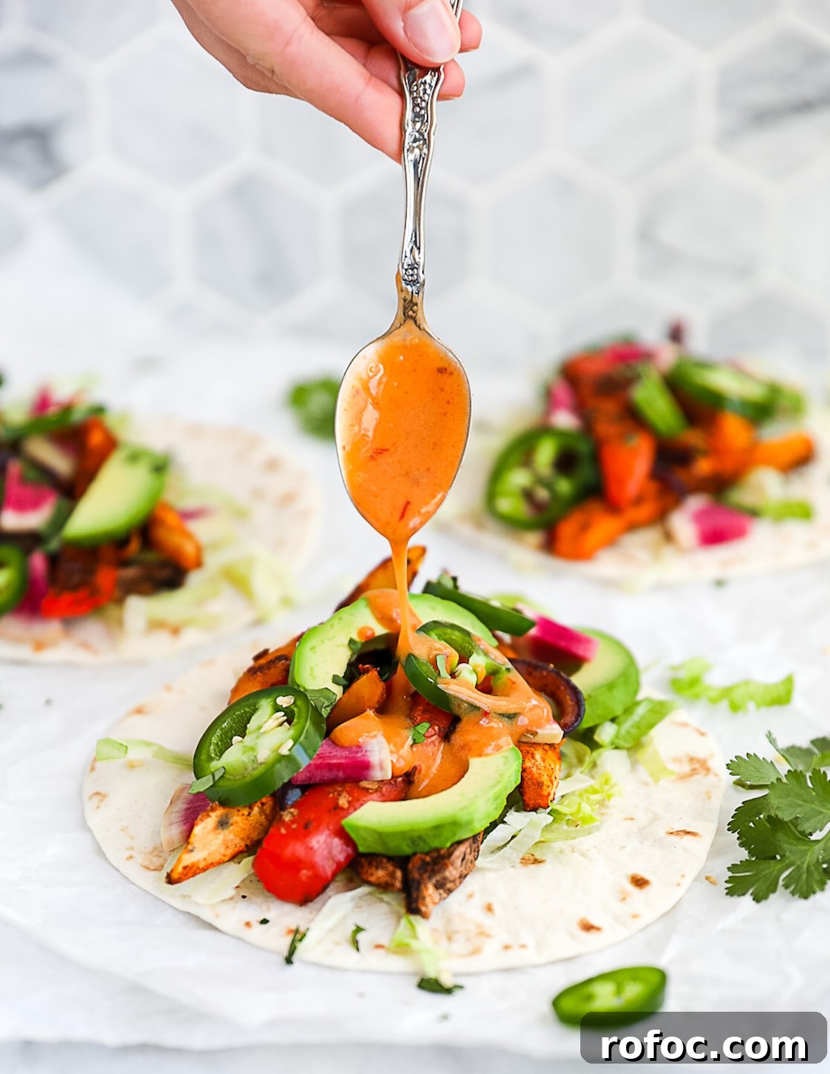 Flavor-Packed Veggie Tacos: Fresh Recipes for Every Night 2 A spoon drizzling chipotle southwest sauce on vegetable tacos.