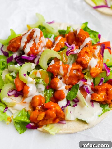 One tortilla with a layer of lettuce, red cabbage, chickpeas, cauliflower, and celery, all with buffalo sauce and ranch dressing on it.