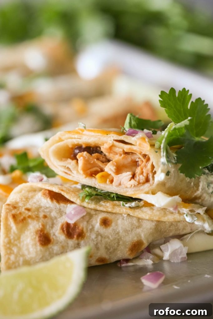 BBQ Chicken Taquitos with Cilantro-Lime Cream Sauce 6 Close up shot of a BBQ Chicken Taquito cut in half, showing the inside of the taquito.