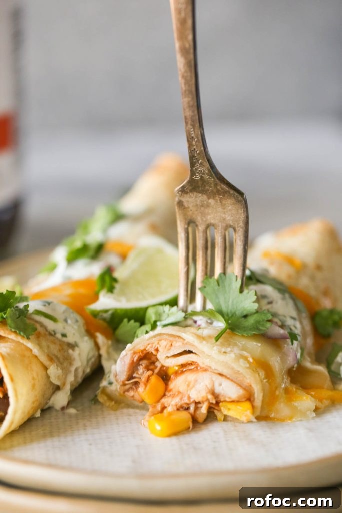 BBQ Chicken Taquitos with Cilantro-Lime Cream Sauce 7 A fork stuck in a BBQ Chicken Taquito on a plate with another BBQ Chicken Taquito.