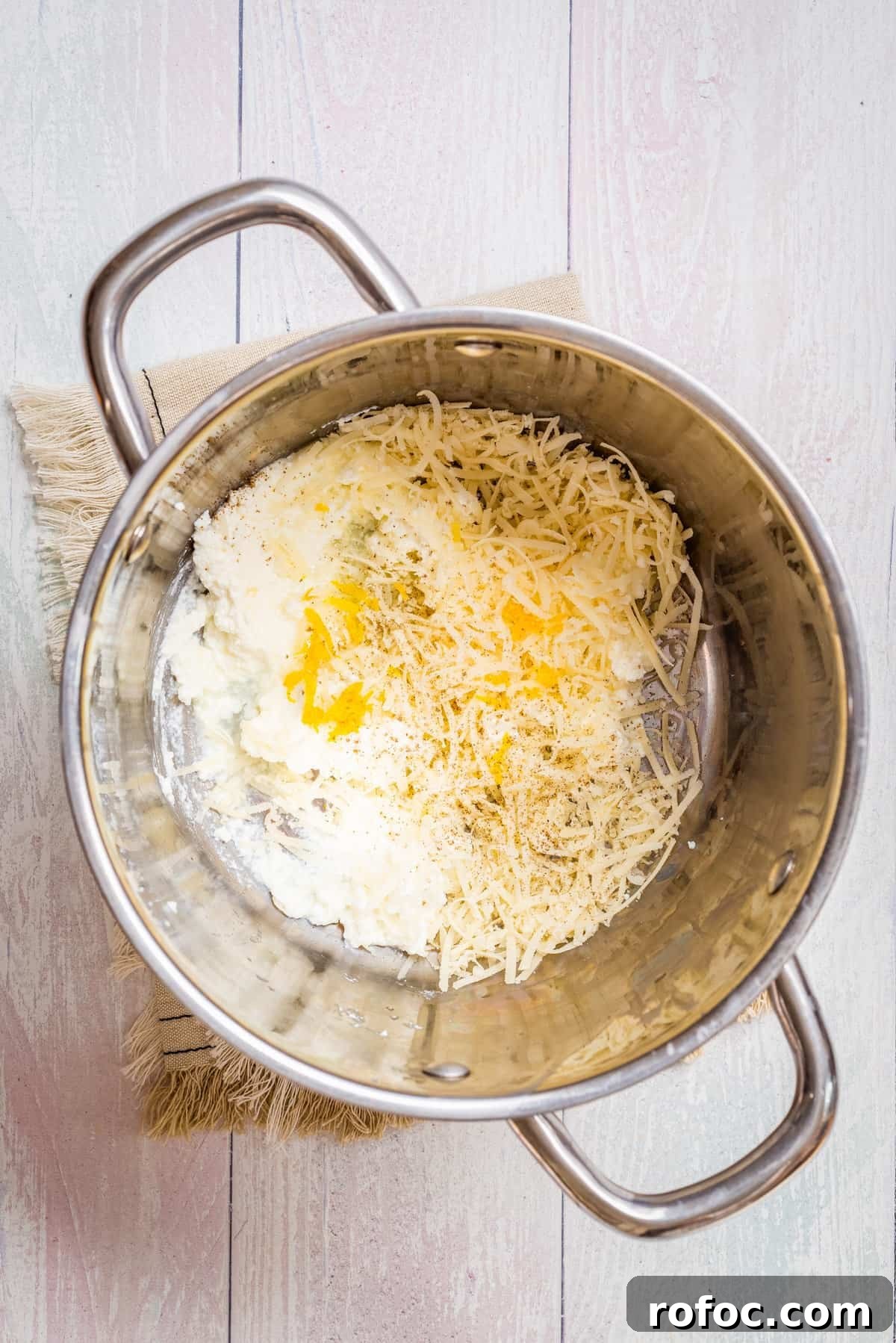 Creamy Lemon Ricotta One-Pot Pasta Recipe 4 Overhead view of a large pot with ricotta, parmesan, lemon zest, lemon juice, salt, and pepper.