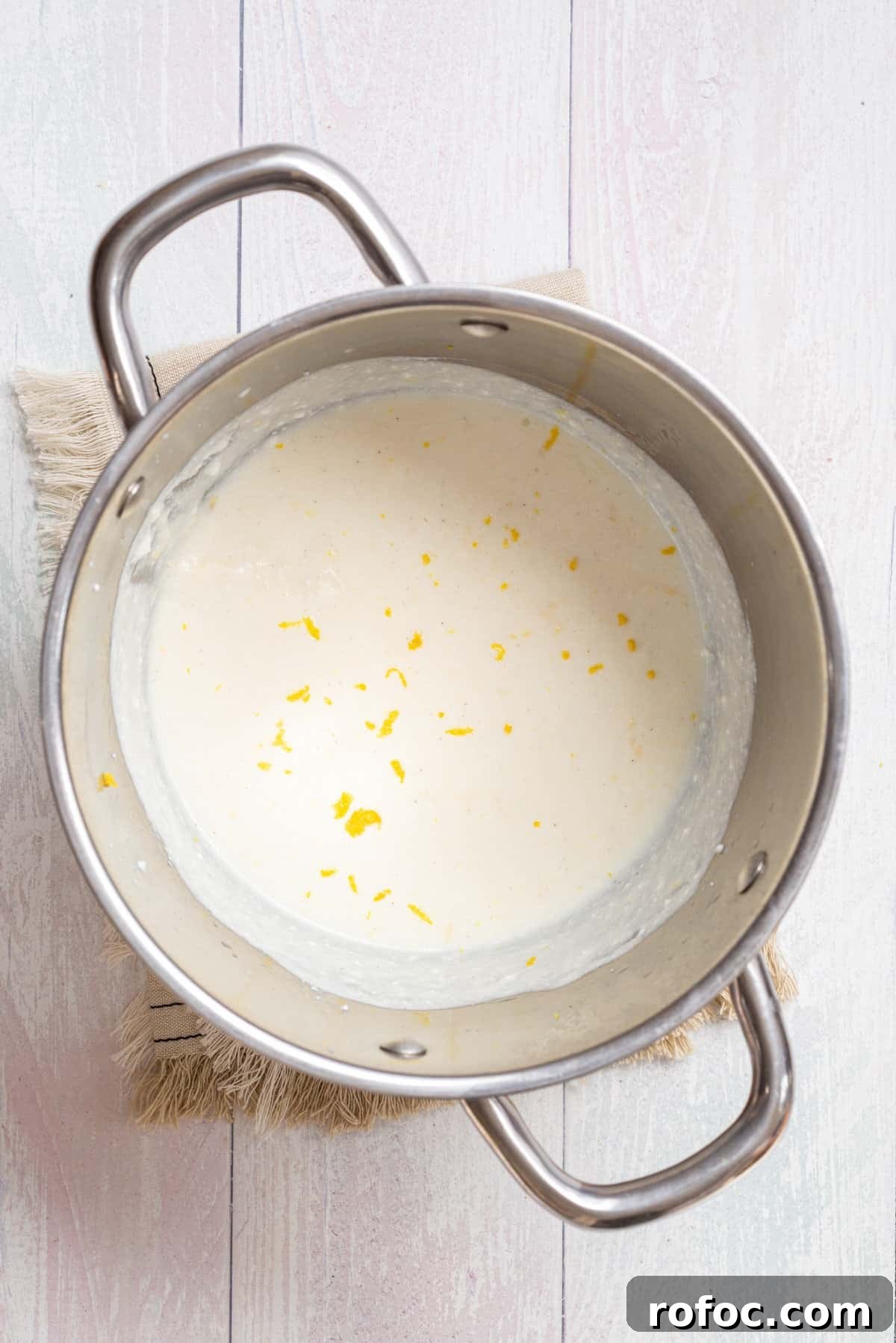 Creamy Lemon Ricotta One-Pot Pasta Recipe 6 Overhead view of a large pot with mixed ricotta, parmesan, lemon zest, lemon juice, salt, and pepper added to pasta water.