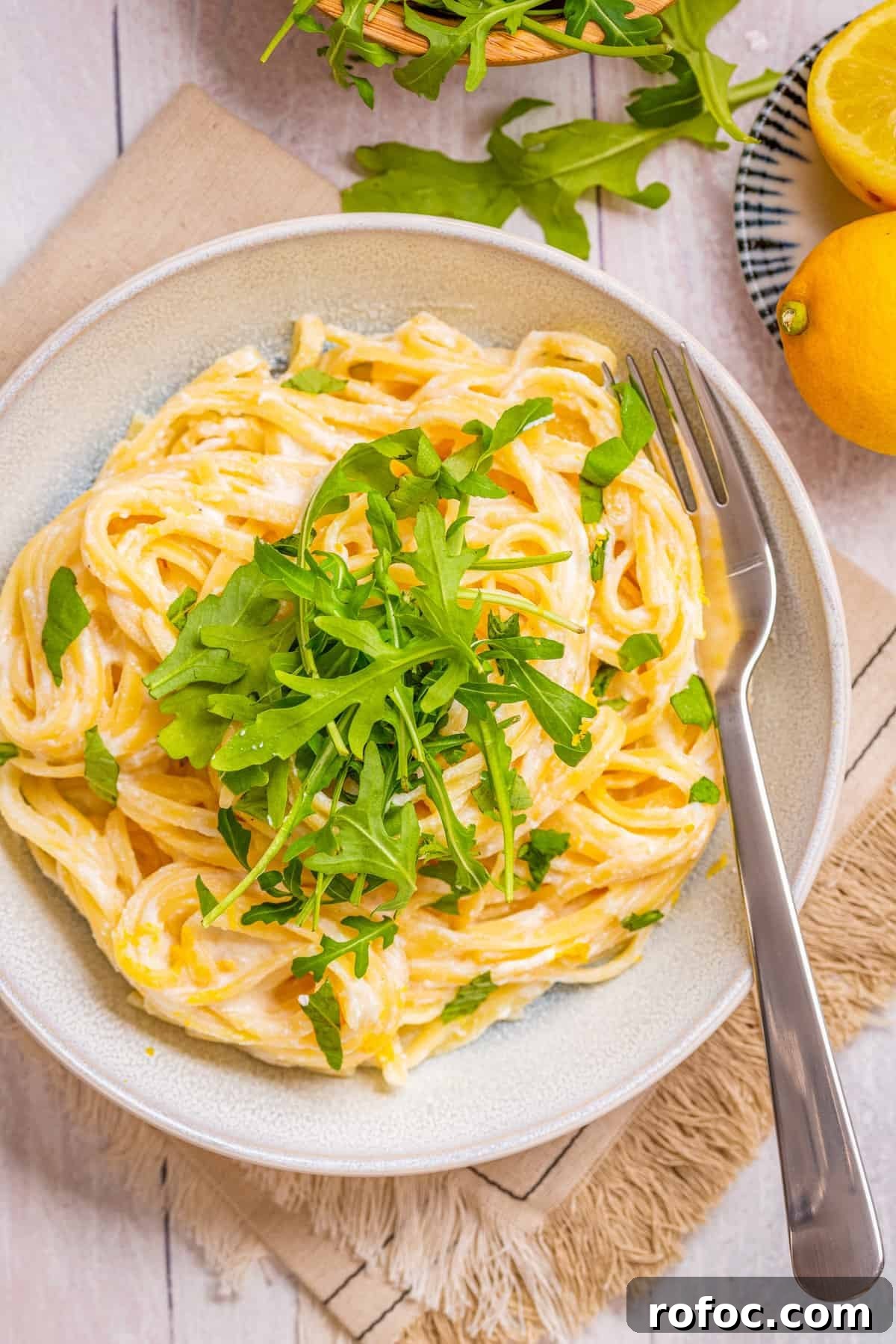 Creamy Lemon Ricotta One-Pot Pasta Recipe 8 Overhead view of cooked one-pot lemon ricotta pasta garnished with rocket and fresh basil leaves, with a fork on the side.