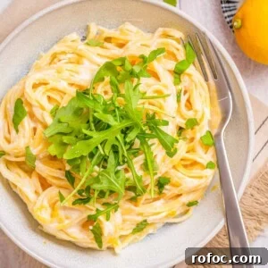Creamy Lemon Ricotta One-Pot Pasta Recipe 9 Overhead view of a plate full of one pot lemon ricotta pasta topped with basil and rocket leaves and a fork on the side.