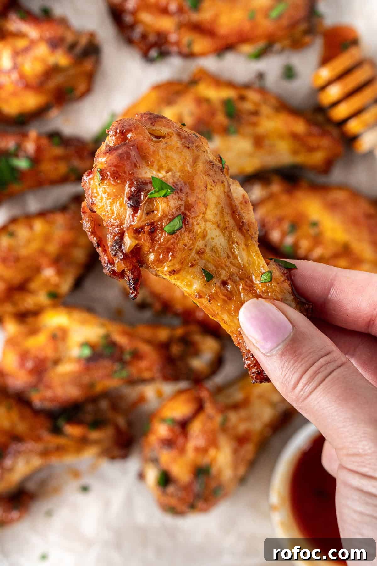 Spicy Honey-Glazed Chicken Wings Recipe for Game Day 11 A hand holding up a hot honey chicken wing.