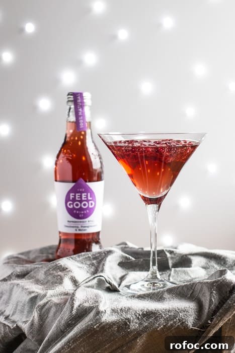 Sparkling Pomegranate Popper Cocktail Recipe for Parties 3 A cocktail glass of Pomagranate Popper Cocktail beside a bottle of Feel Good Cranberry and Pomagranate juice