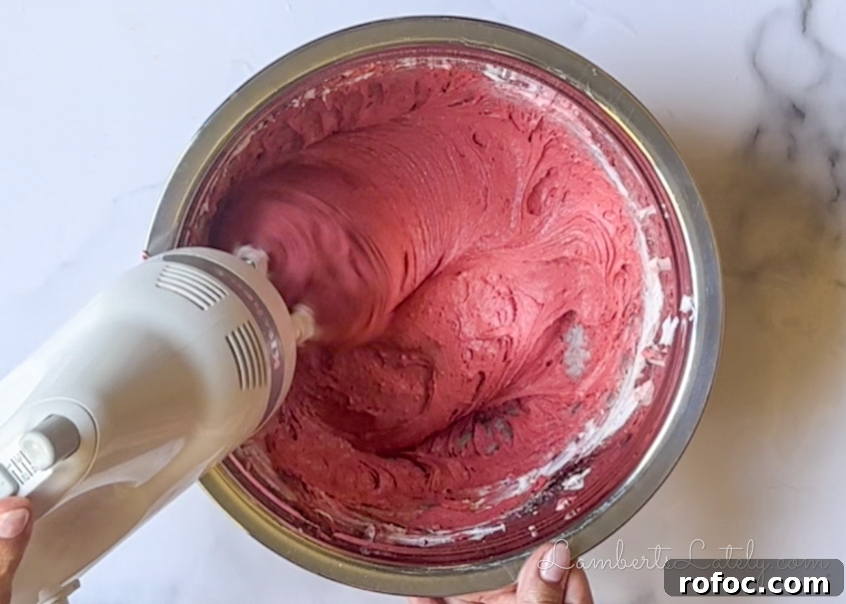 mixing red velvet cookie batter with a hand mixer.