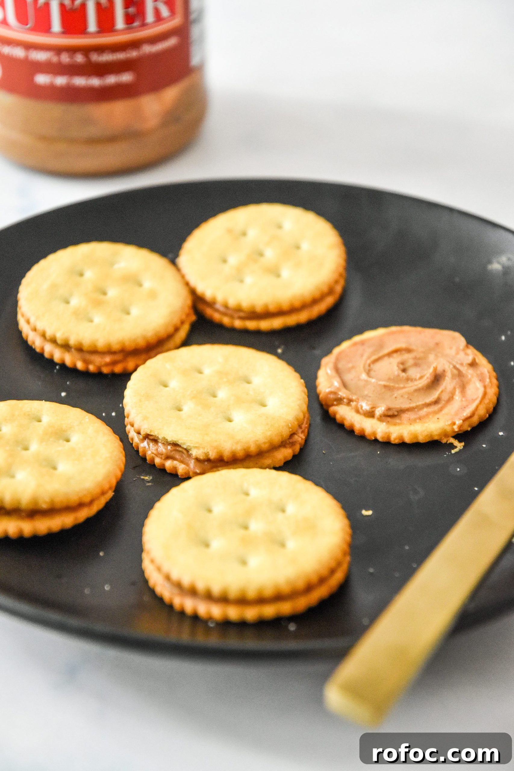 spreading peanut butter on crackers with a butter knife.