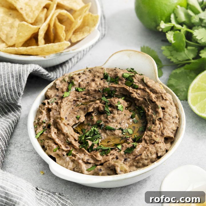 black bean hummus in a white dish next to tortilla chips